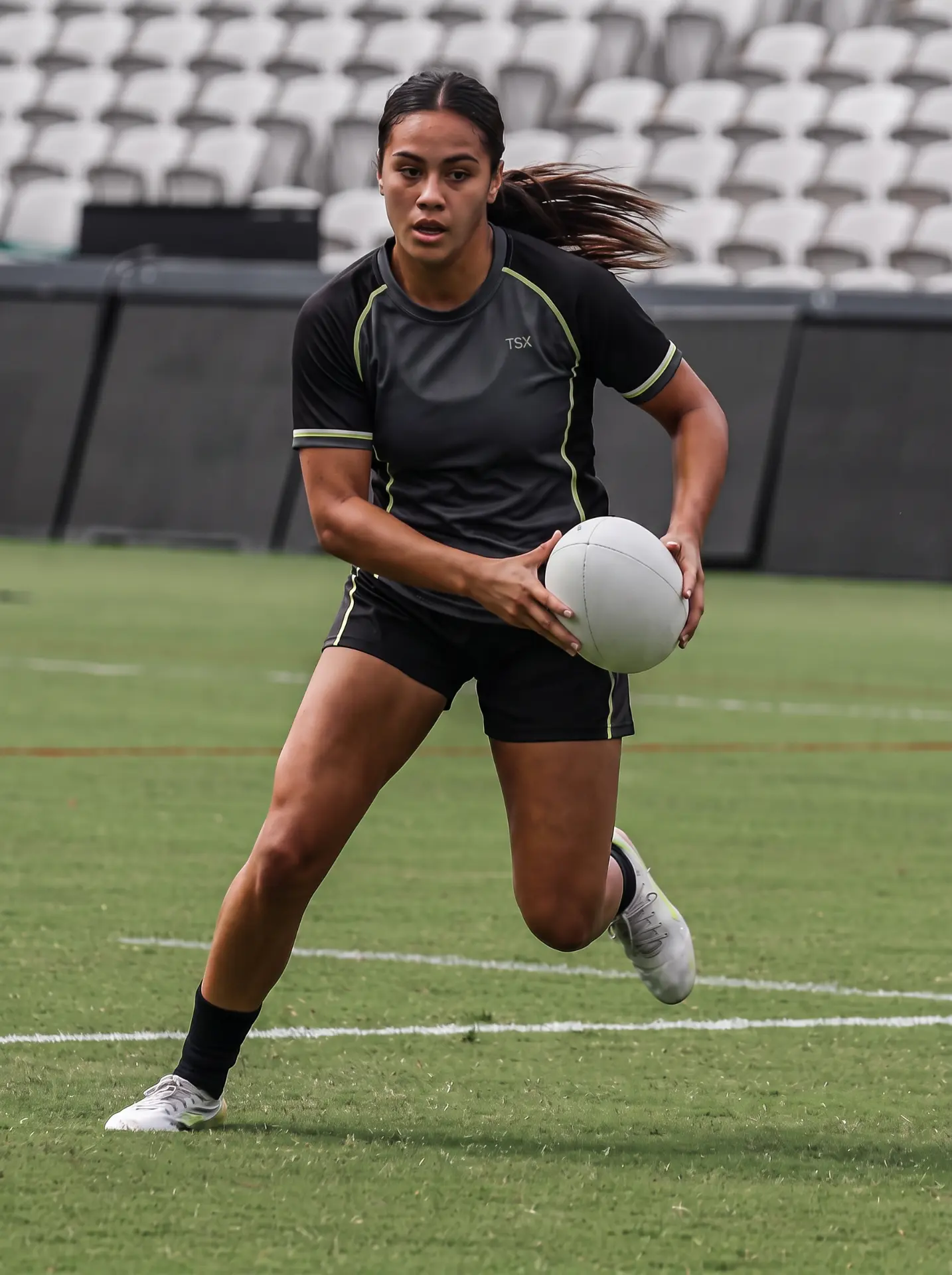 A female rugby league player running with the ball during a game.