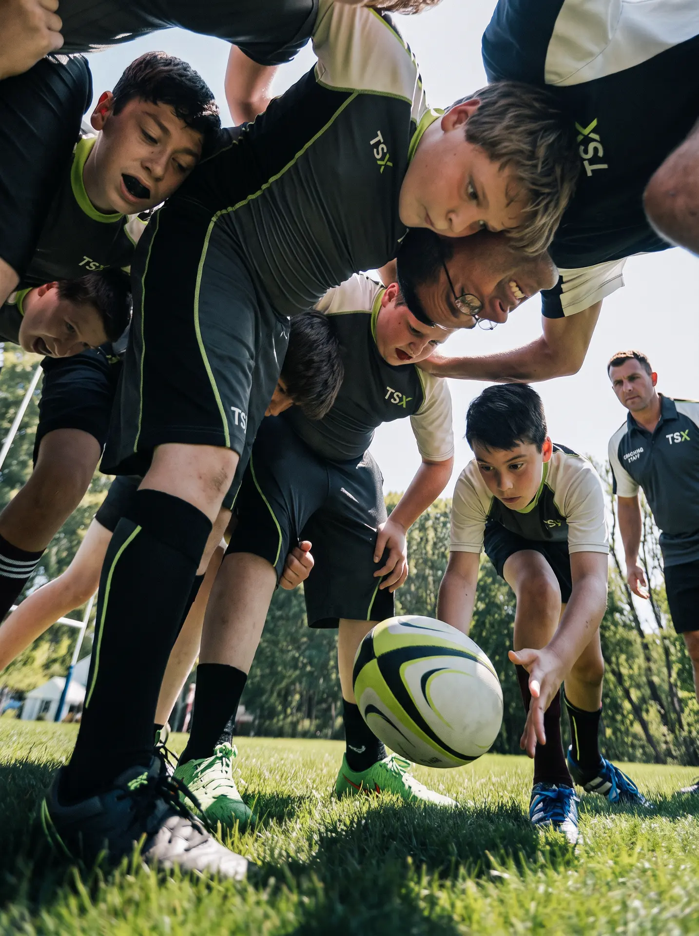 A junior rugby league team gathered in a huddle with their coach.